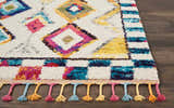 Close-up of the Nourison Nomad Ivory Multicolor Tribal Area Rug with diamond pattern and colorful tassels.