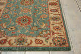 Close-up of the aqua Nourison Living Treasures rug, featuring a traditional floral pattern and a beige border on a wood floor.