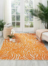 Bright living room with Nourison Aloha Orange contemporary rug, white sofa, and large windows.