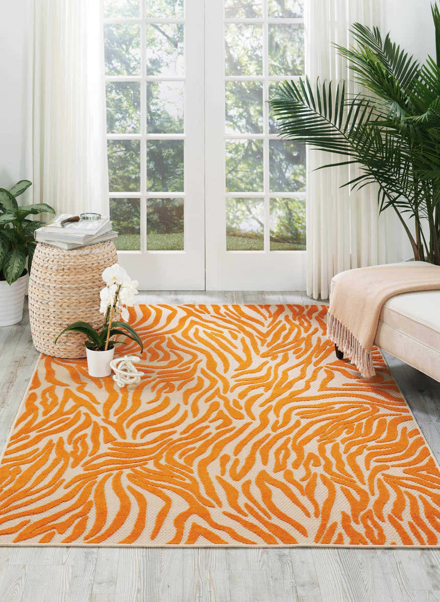 Bright living room with Nourison Aloha Orange contemporary rug, white sofa, and large windows.