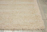 Close-up of the plush texture of the Nourison Amore Cream Shag Rug on light wood flooring.