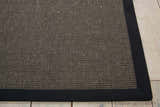Close-up of the textured Michael Amini Brilliance Charcoal rug with a dark border on light wood floors.