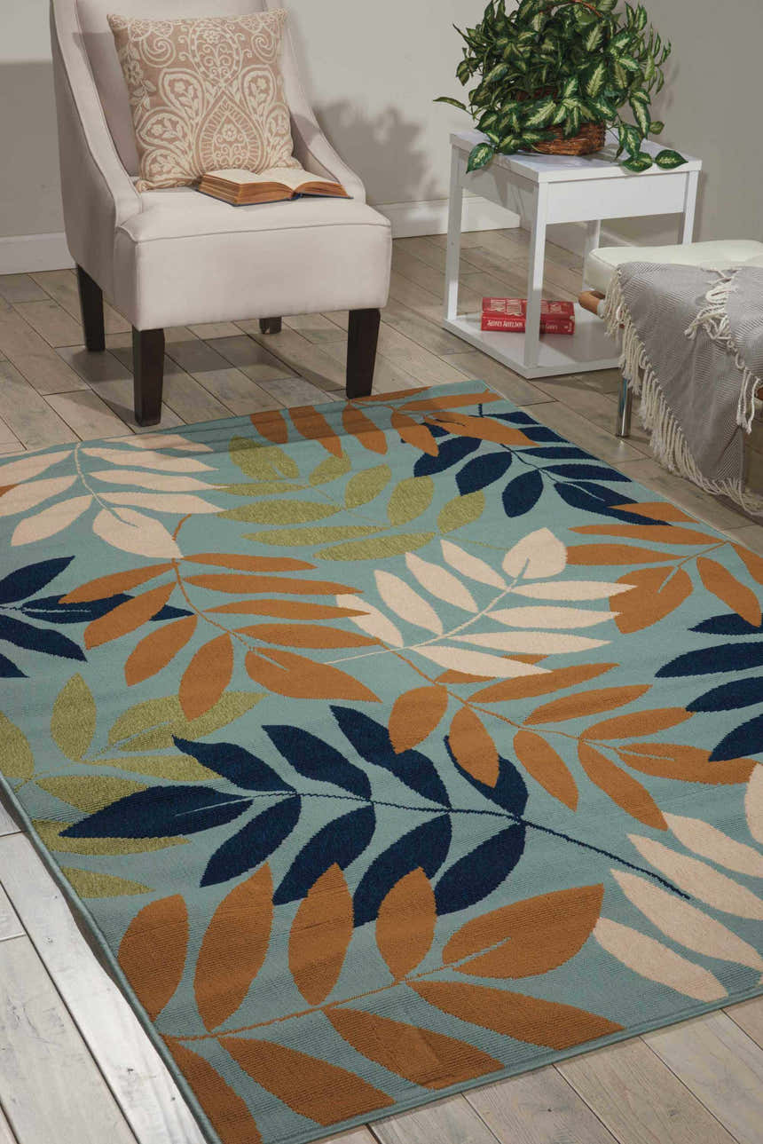 Living room scene with a light blue Nourison Caribbean area rug featuring a contemporary leaf pattern.