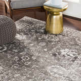 Close-up of Tripp Distressed Gray Rug in a living room setting with a gray pouf and gold accent table. Roomscene-Rectangle