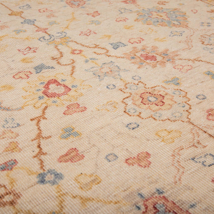 Close-up of the hand-knotted Rizzy TUS713 area rug, featuring beige wool with blue, red, and yellow floral accents. Texture