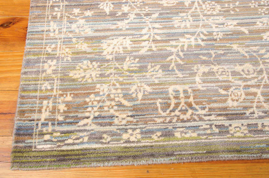 Close up of the Nourison Rhapsody Blue Moss rug showing the wool texture, floral pattern, and blue, green, and brown colors.