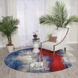 Living room scene with a round Nourison Twilight Multicolor rug, white chair, and palm trees. Modern style.