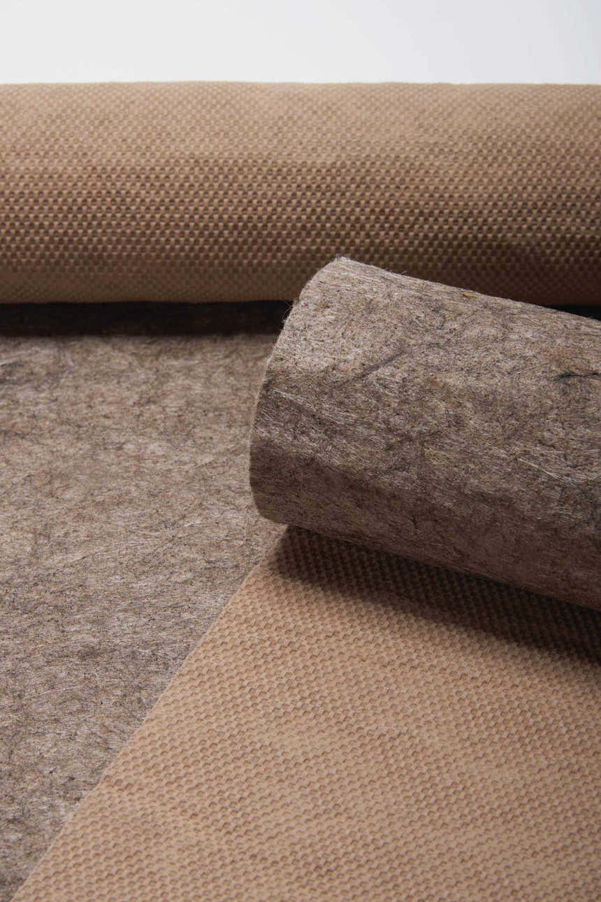 Close-up of a rolled Nourison Loc Non-slip Pad Area Rug showing its texture and gray color.