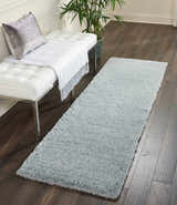 Entryway scene with a Nourison Malibu Shag Slate rug, white bench, silver pillow, and dark wood floors.