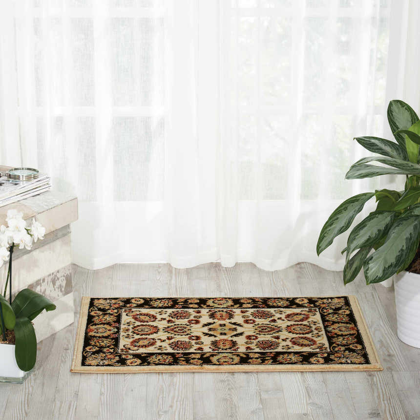 Bright room scene with Nourison Delano Ivory Black rug. Chestnut floral pattern, black border, on light wood floor.