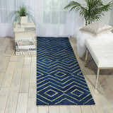 Light-filled room with Barclay Butera Intermix Storm rug, geometric pattern. White bench, plants, and light wood floors.