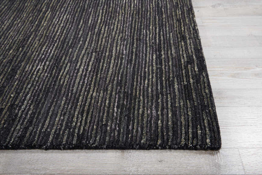 Close-up of the Onyx Nourison OCEAN rug. Black rug with a vertical striped pattern on light gray wood floors.