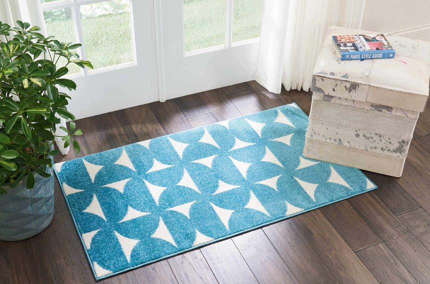 Entryway with Nourison Harper Blue Colorful Indoor Area Rug, wood floors, white door, and potted plant.