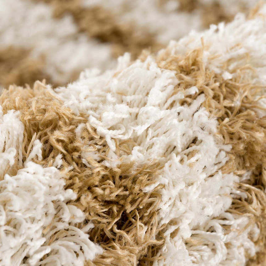 Close-up of the Calup Shag Area Rug showing its bone and nutmeg colors and soft, shaggy texture. Fold