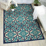 Living room scene with a Nourison Aloha Navy Bohemian Area Rug, white bench, and wood floors.