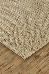 Close-up of the hand woven Feizy Kaelani rug. Tan, ivory, and taupe jute rug on a wood floor. Corner