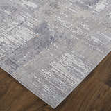 Close up of the Feizy Lennon rug in taupe, tan, and blue with an abstract pattern on a hardwood floor. Corner