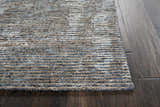 Close up of the textured Nourison Ellora Slate rug in taupe and blue on a dark wood floor.