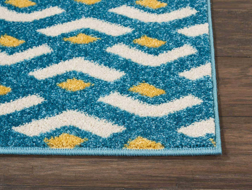 Close-up of Nourison Harper Blue rug showing colorful geometric pattern with blue, white, and yellow on wood floor.