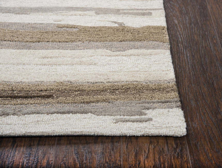 Close-up of the hand-tufted Rizzy VOG101 area rug. Beige, tan, and gray stripes on a textured wool rug on dark wood floors. Corner
