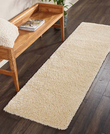 Hallway scene with a Nourison Malibu Shag Cream runner rug, wood bench, and dark wood floors.
