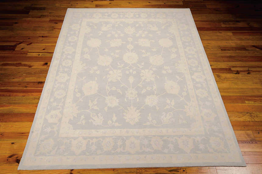 Close-up of the Nourison Zephyr Light Blue rug showing floral pattern and border on hardwood floor.