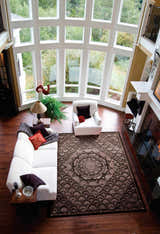 Living room with white sofa and Nourison Regal Espresso Persian rug, featuring a large window and fireplace.
