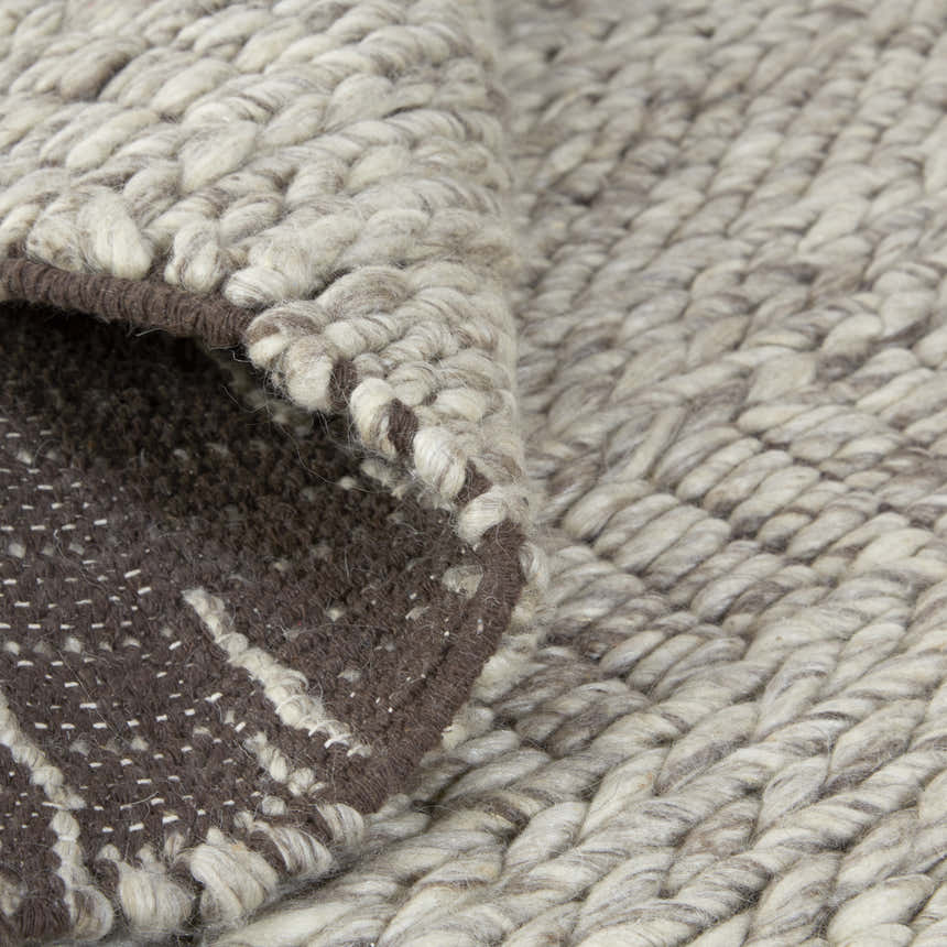 Close-up of the hand-woven Feizy Berkeley rug. Ivory, gray, and tan wool with geometric pattern and brown backing. Fold