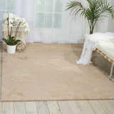 Light, airy room with a sandstone Nourison Escalade Sand Indoor Area Rug, white daybed, and orchids.