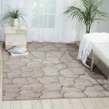 Bright room scene with a gray Nourison Utopia Granite rug, white bench, and plants.