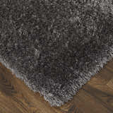 Close-up of the plush texture and corner of a gray Feizy Darian area rug on a wood floor. Corner