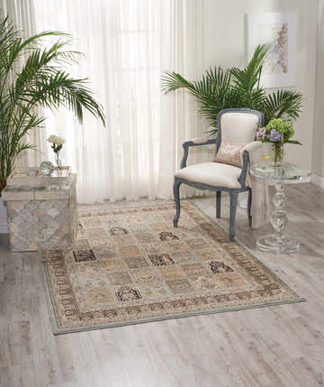 Living room scene with a Nourison Ararat Blue Persian rug, chair, plants, and light wood floors.
