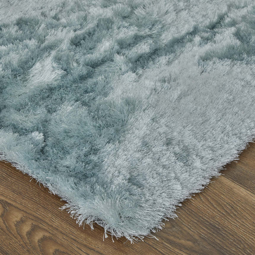 Close-up of the plush Feizy Indochine Modern Solid rug in blue and silver, showing texture and corner on wood floor. Swatch