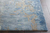 Close up of the Nourison Prismatic Denim rug showing its abstract pattern, texture, and colors on a dark wood floor.
