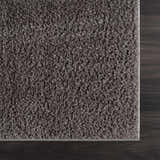 Close-up of the Judy Solid Dark Gray Washable Shag Rug showing its plush texture and color against dark wood flooring. Swatch