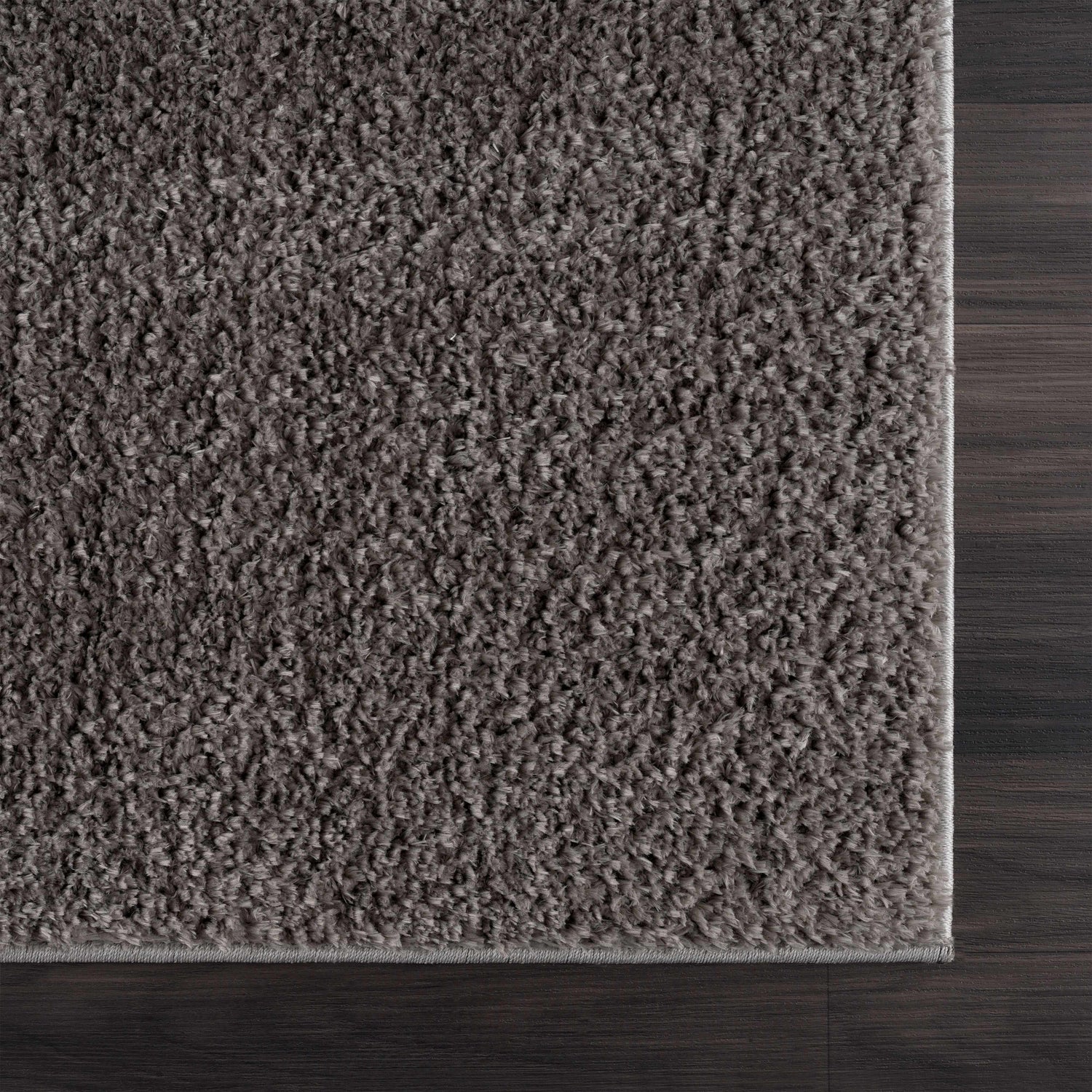 Close-up of the Judy Solid Dark Gray Washable Shag Rug showing its plush texture and color against dark wood flooring. Swatch