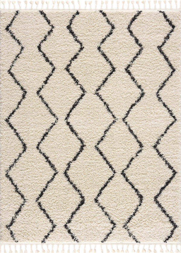 Close-up of the West End Plush Area Rug. Light beige shag rug with a charcoal geometric diamond pattern and fringe. Design-Rectangle
