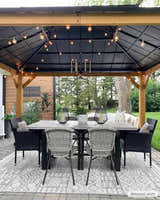 Outdoor dining area with a gray table and the Luddenham Textured Outdoor Rug in black and white underfoot. Roomscene-Rectangle