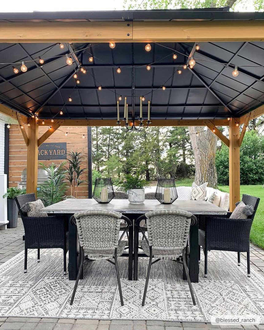 Outdoor dining area with a gray table and the Luddenham Textured Outdoor Rug in black and white underfoot. Roomscene-Rectangle