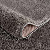 Close-up of the Judy Solid Dark Gray Washable Shag Rug showing its plush texture and bound edge. Fold