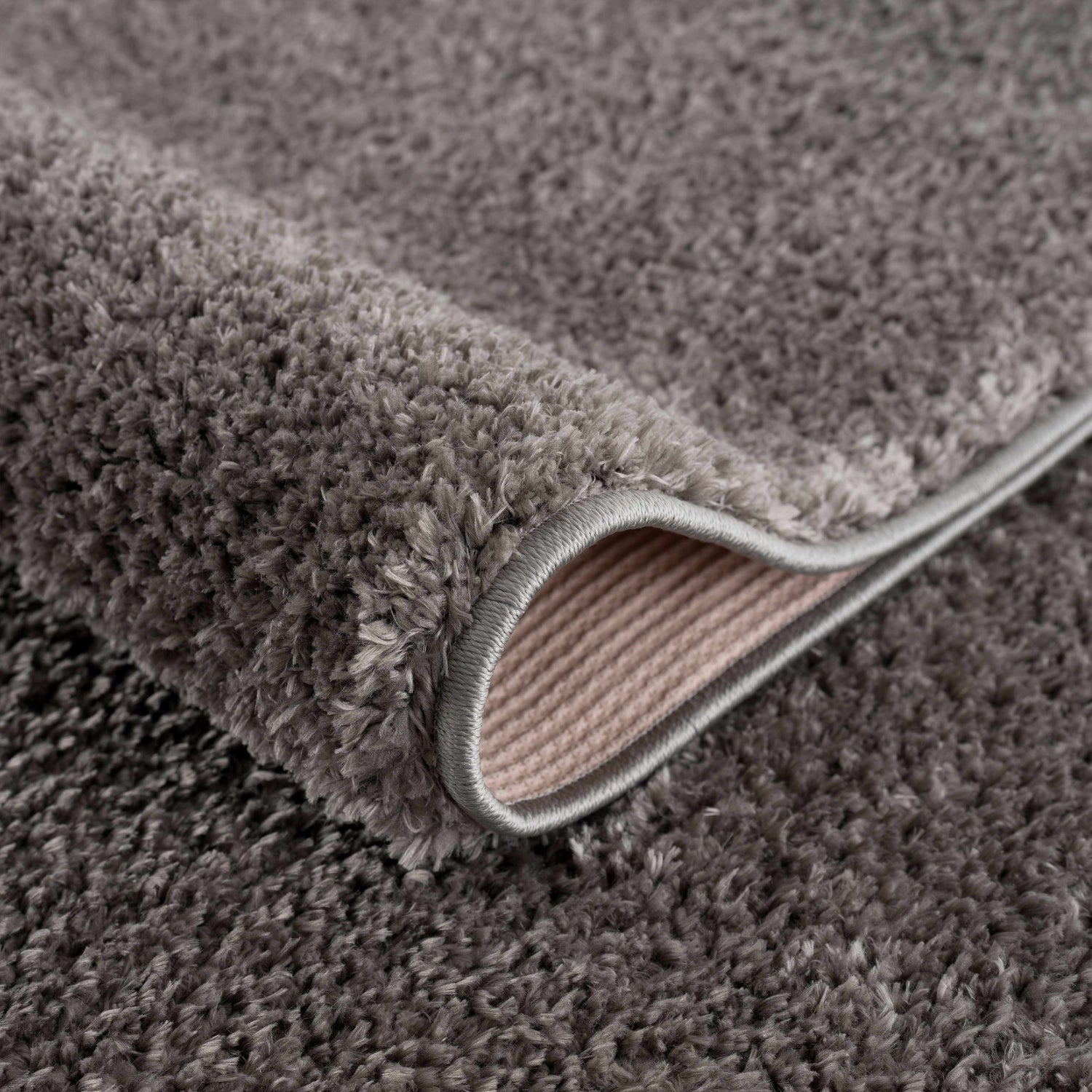 Close-up of the Judy Solid Dark Gray Washable Shag Rug showing its plush texture and bound edge. Fold