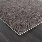 Close-up of the Judy Solid Dark Gray Washable Shag Rug showing its plush texture and dark gray color on dark wood flooring. Corner