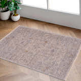 Entryway scene with the Ayarn Thick Luxe Statement Rug in brown, charcoal, and gray on wood floors near a white door and potted plants. Roomscene-Rectangle