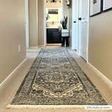 Hallway with a gray Ailsa Area Rug runner leading to a bathroom. Neutral walls, white doors, and a plant add style. Roomscene-Runner