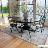 Dining room with round wood table and black chairs on Anzu Washable Rug. Gray traditional rug anchors the space. Roomscene-Rectangle