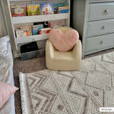Kids room scene with a beige Armen Area Rug, small chair, bookshelf, and gray dresser. Neutral tones create a calming space. Roomscene-Rectangle