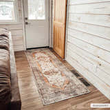 Entryway with brown leather couch and Arncliffe Washable Area Rug runner in orange, tan, and ivory. Roomscene-Runner