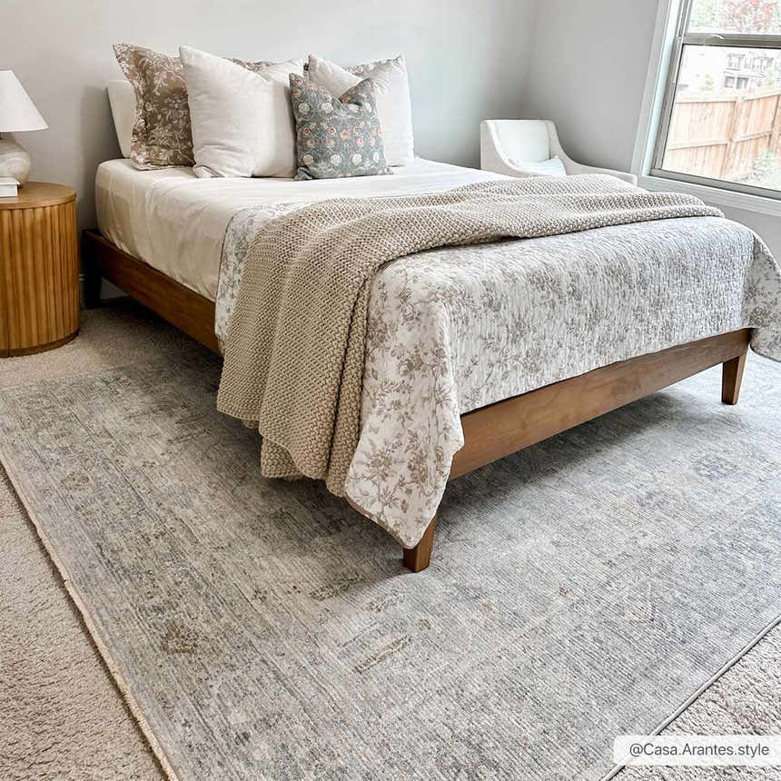 Bedroom scene with Ayarn Thick Luxe Statement Rug in gray, under a wood bed with neutral bedding and a knitted throw. Roomscene-Rectangle
