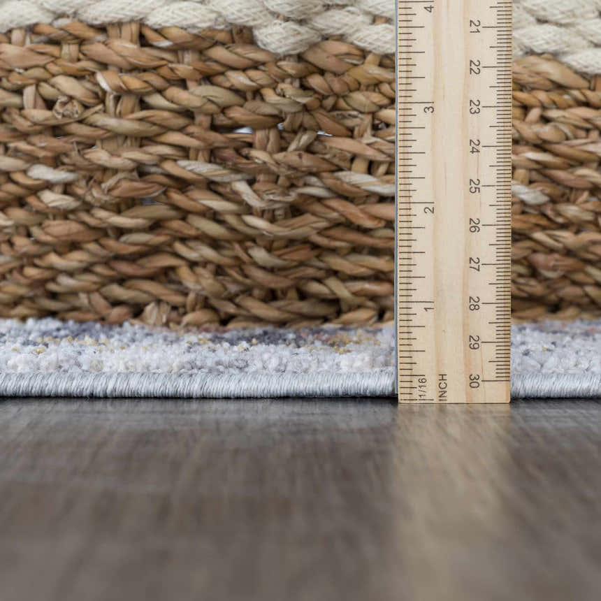 Close-up of the Jurou Area Rug showing the light gray, natural gray colors, texture, and rug thickness with a ruler. Pile