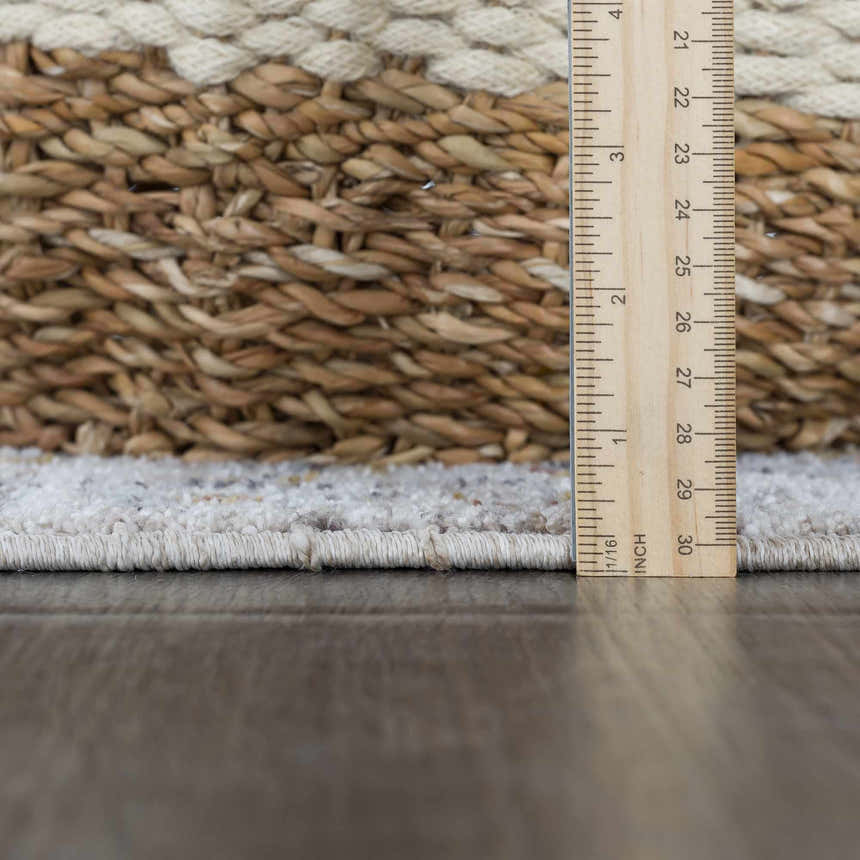 Close-up of the Ivria Blue Gray Area Rug showing the rug's pile height with a ruler and a decorative basket. Pile